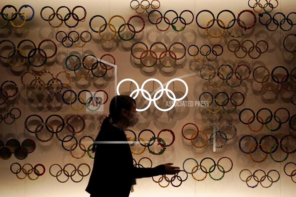 FILE - In this Aug. 31, 2020, file photo, a staff gestures at Japan Olympic Museum where a lantern containing the Olympic Flame shown prior to public display, in Tokyo. The postponed Tokyo Olympics are to open in just under nine months, and there are still far more questions than answers. Organizers and the International Olympic Committee say they are working on a vast number of contingency plans to hold the Games in the midst of a pandemic. (AP Photo/Eugene Hoshiko, File)