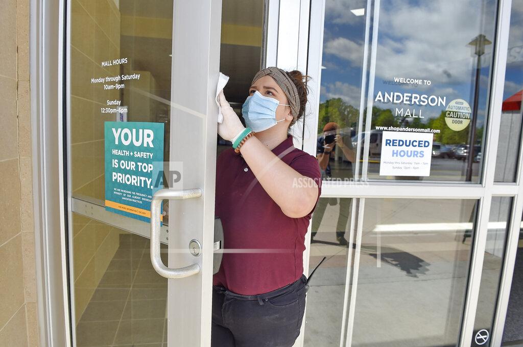Richard Shiro Kendall Ballew an employee of the Anderson Mall cleans the doors before the mall opened to limited business on Friday, April 24, 2020 in Anderson, S.C. The mall opened to limited business after South Carolina Governor Henry McMaster eased restrictions due to coronavirus concerns. (AP Photo/Richard Shiro)