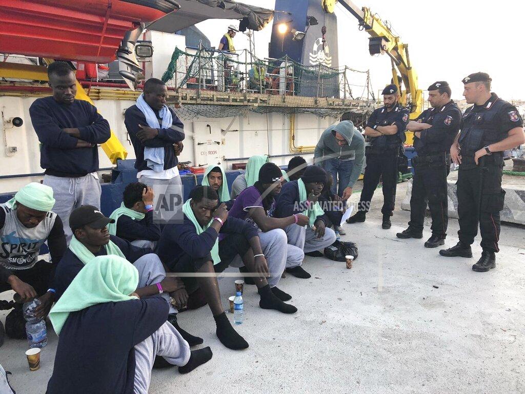 Annalisa Camilli FILE -- In this file photo migrants sit on the quay after disembarking at Lampedusa harbor, Italy, on June 29, 2019. Small boats filled with more Tunisian migrants have reached a tiny Italian island, which had no room to quarantine them Saturday, Aug. 1, 2020, amid the pandemic. Sicilian daily Giornale di Sicilia quoted Lampedusa Mayor Toto' Martello as saying the island can’t wait until the government sends a ferry as promised so they can be safely isolated for 14 days as part of anti-COVID-19 measures. (AP Photo/Annalisa Camilli)