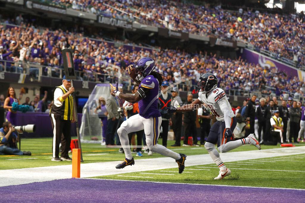 Minnesota Vikings running back Dalvin Cook (4) scores on a 5-yard touchdown run ahead of Chicago Bears cornerback Jaylon Jones (31) during the first half of an NFL football game, Sunday, Oct. 9, 2022, in Minneapolis. (AP Photo/Bruce Kluckhohn)