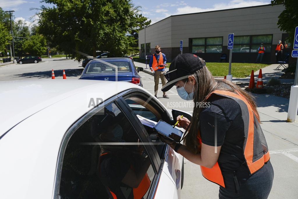 Poll worker Kellie Madsen helps a voter lined up at one of twelve drive-up voting assistance centers in Salt Lake County, Utah, at the Northwest Recreation Center on Tuesday, June 30, 2020, as workers go to cars to help people get ballots to replace lost ones or help unaffiliated voters register Republican to be able to vote in the primary. (Francisco Kjolseth/The Salt Lake Tribune via AP)