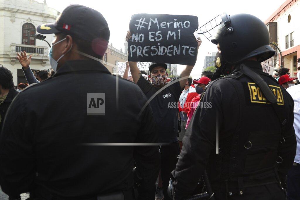 Martin Mejia A supporter of ousted President Martin Vizcarra holds a sign with a message that reads in Spanish: "Merino is not my president," as people refusing to recognize the new government march in downtown Lima, Peru, Wednesday, Nov. 11, 2020. On Tuesday, Peru swore in Manuel Merino as president, after Peru's legislature booted Vizcarra from office on Monday. (AP Photo/Martin Mejia)