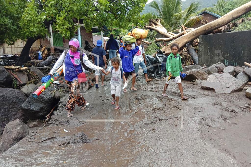 Ricko Wawo People walk amid debris at a village affected by flood in Ile Ape, on Lembata Island, East Nusa Tenggara province, Indonesia, Sunday, April 4, 2021 photo. Multiple disasters caused by torrential rains in eastern Indonesia have left dozens of people dead or missing while displacing thousands, the country's disaster relief agency said Monday. (AP Photo/Ricko Wawo)