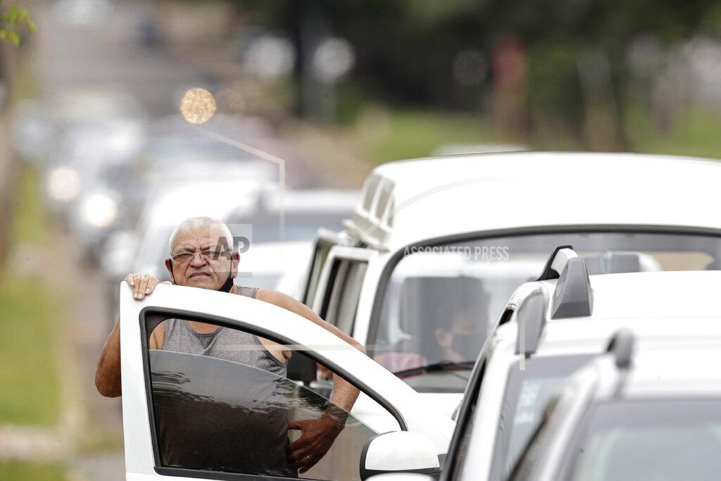 Eraldo Peres FILE - In this March 22, 2021 file photo, a man stands next to his vehicle in a line at a COVID-19 vaccination point for priority elderly persons in the Ceilandia neighborhood, on the outskirts of Brasilia, Brazil. As Brazil hurtles toward an official COVID-19 death toll of 500,000, its Senate is publicly investigating how the pandemic death toll got so high, focusing on why the government ignored opportunities to buy vaccines while pushing hydroxychloroquine. (AP Photo/Eraldo Peres, File)