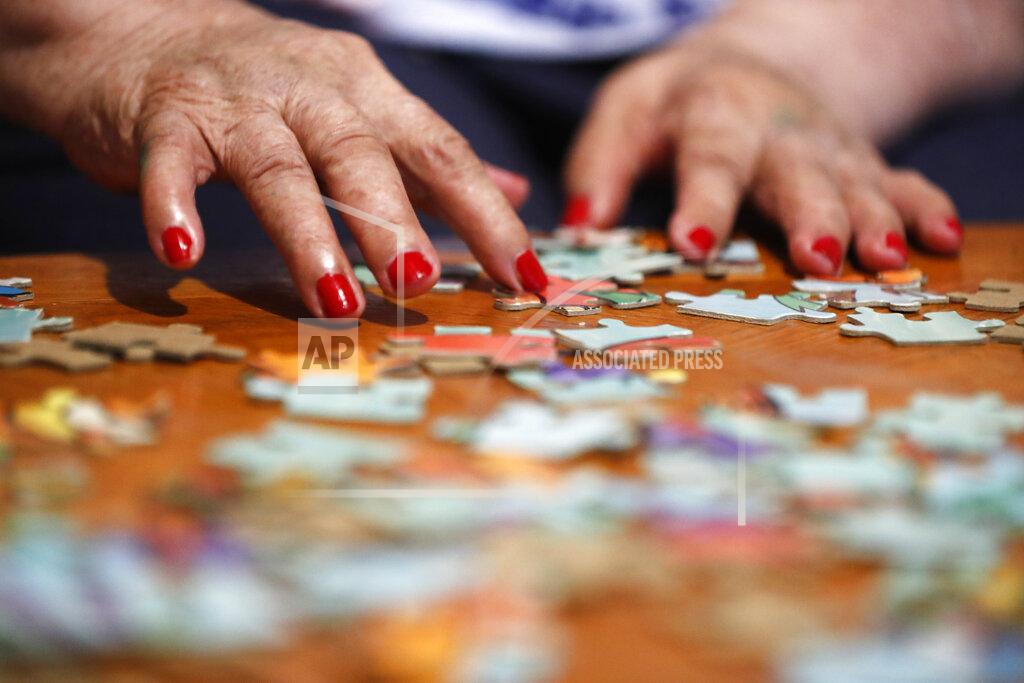 Shafkat Anowar Francisca Perez, 84, rearranges puzzle pieces, a part of her regular exercise to recover from rheumatoid arthritis, Wednesday, June 30, 2021, in Chicago's Little Village neighborhood. She suffers from a heart condition and depression, among other ailments. Her daughter, Eugenia Rodriguez, hasn't been eligible for insurance coverage after overstaying a visitor visa from Mexico. She used to wake up every two or three hours at night to check on her mother. Since getting health insurance through the Illinois program, her mother has all the medications she needs. (AP Photo/Shafkat Anowar)