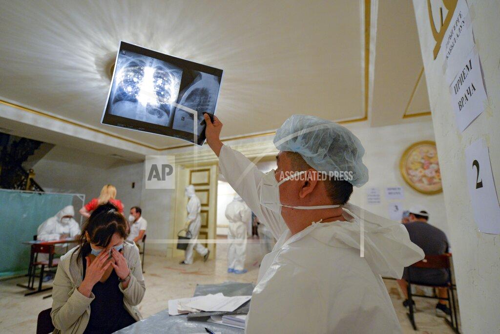 Vladimir Voronin A medical specialist, wearing a protective suit, checks a young woman's, lung X-ray inside a restaurant that was converted into a clinic in Bishkek, Kyrgyzstan, Wednesday, July 22, 2020. The restaurant in the center of Bishkek was converted into a night-time clinic to support the country's health care system, struggling with the coronavirus outbreak. Doctors and nurses from other facilities work there and treat people between 8 p.m. and 8 a.m. (AP Photo/Vladimir Voronin)