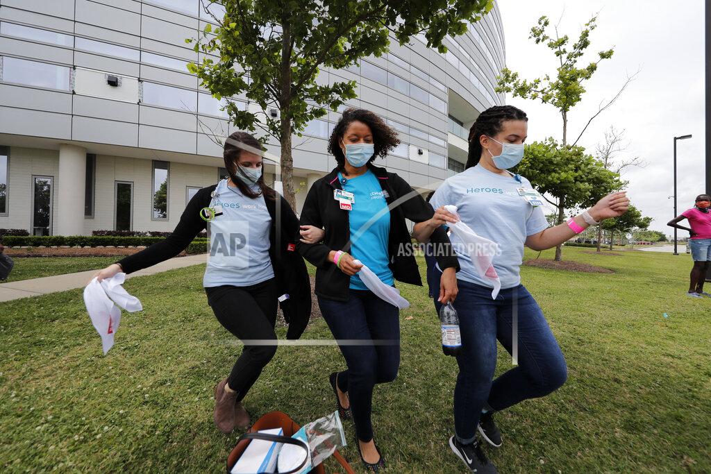 Healthcare workers at New Orleans East Hospital wave handkerchiefs and dance to a jazz serenade, as a tribute for their care of COVID-19 patients, by the New Orleans Jazz Orchestra, outside the hospital in New Orleans, Friday, May 15, 2020. A New York woman collaborated with the New Orleans Jazz Orchestra to put on what she calls a stimulus serenade to give moral support to front-line hospital workers and COVID-19 patients in New Orleans (AP Photo/Gerald Herbert)