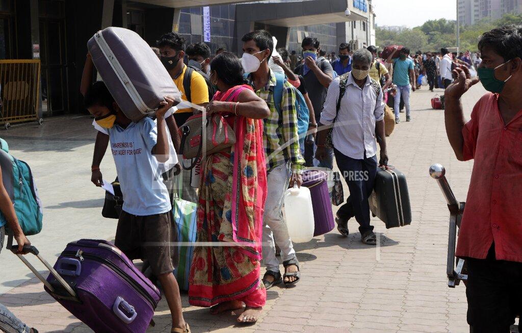 Rajanish Kakade People wearing masks as a precaution against the coronavirus stand in a queue to board trains at Lokmanya Tilak Terminus in Mumbai, India, Friday, April 16, 2021. Migrant workers are swarming rail stations in India's financial capital Mumbai to go to their home villages as virus-control measures dry up work in the hard-hit region. The government of Maharashtra state imposed lockdown-like curbs on Wednesday for 15 days to check the spread of the virus. It closed most industries, businesses and public places and limited the movement of people, but didn’t stop the bus, train and air services. An exodus ensued, with panicked day laborers hauling backpacks onto overcrowded trains leaving Mumbai, travel that raises fears of infections spreading in rural areas. (AP Photo/Rajanish Kakade)