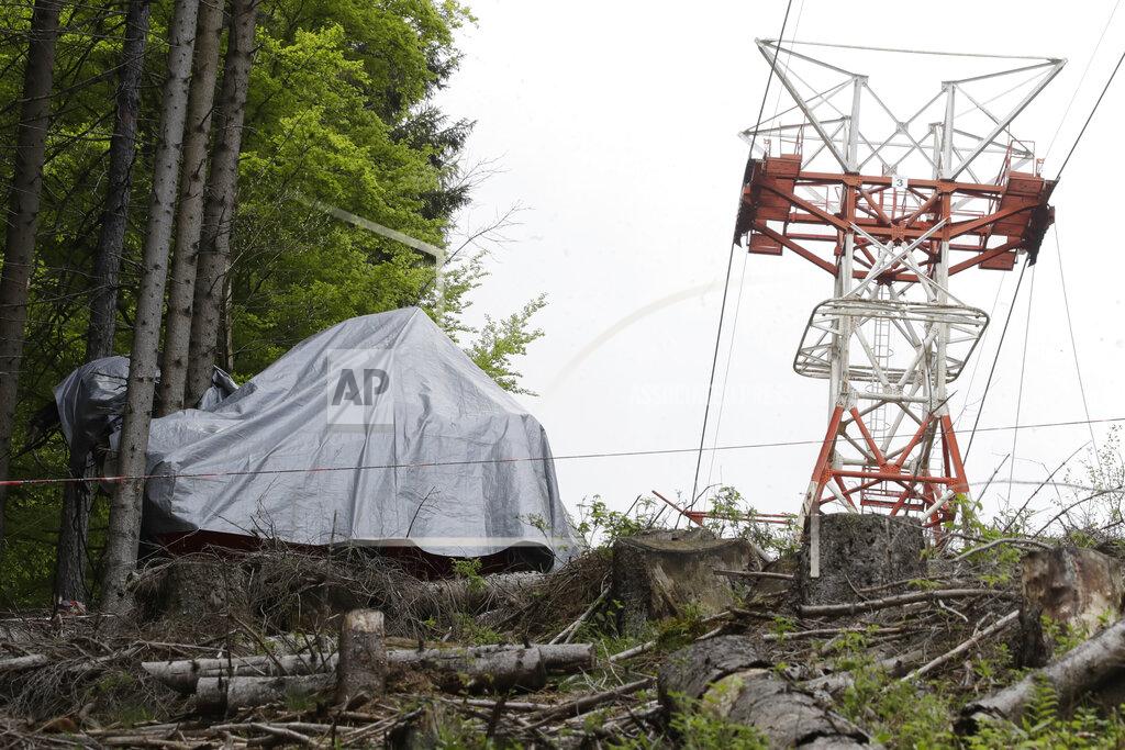Luca Bruno The wreckage of a cable car after it collapsed near the summit of the Stresa-Mottarone line in the Piedmont region, northern Italy, Wednesday, May 26, 2021. Police have made three arrests in the cable car disaster that killed 14 people after an investigation showed a clamp, placed on the brake as a patchwork repair effort, prevented the brake from engaging after the lead cable snapped. (AP Photo/Luca Bruno)
