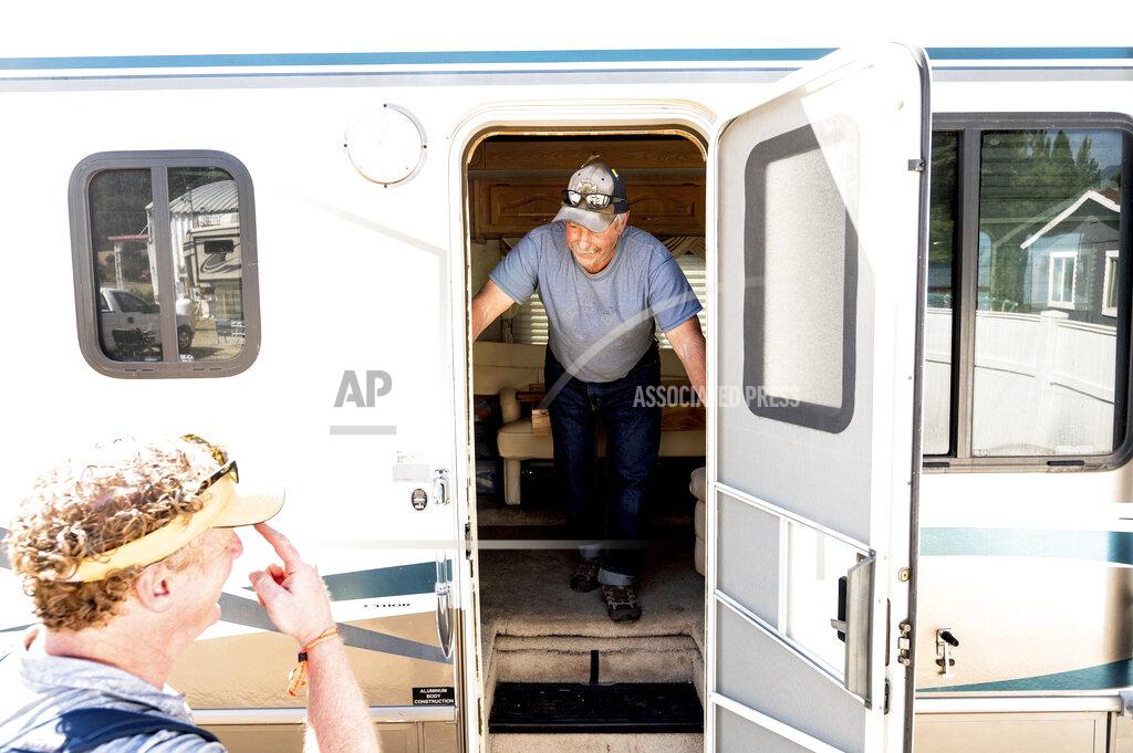 Noah Berger Volunteer firefighter John Hunter looks out from a donated motorhome he received from Woody Faircloth, left, on Sunday, Sept. 5, 2021, in Quincy, Calif. Hunter lost his home and hardware store to the Dixie Fire in August. (AP Photo/Noah Berger)