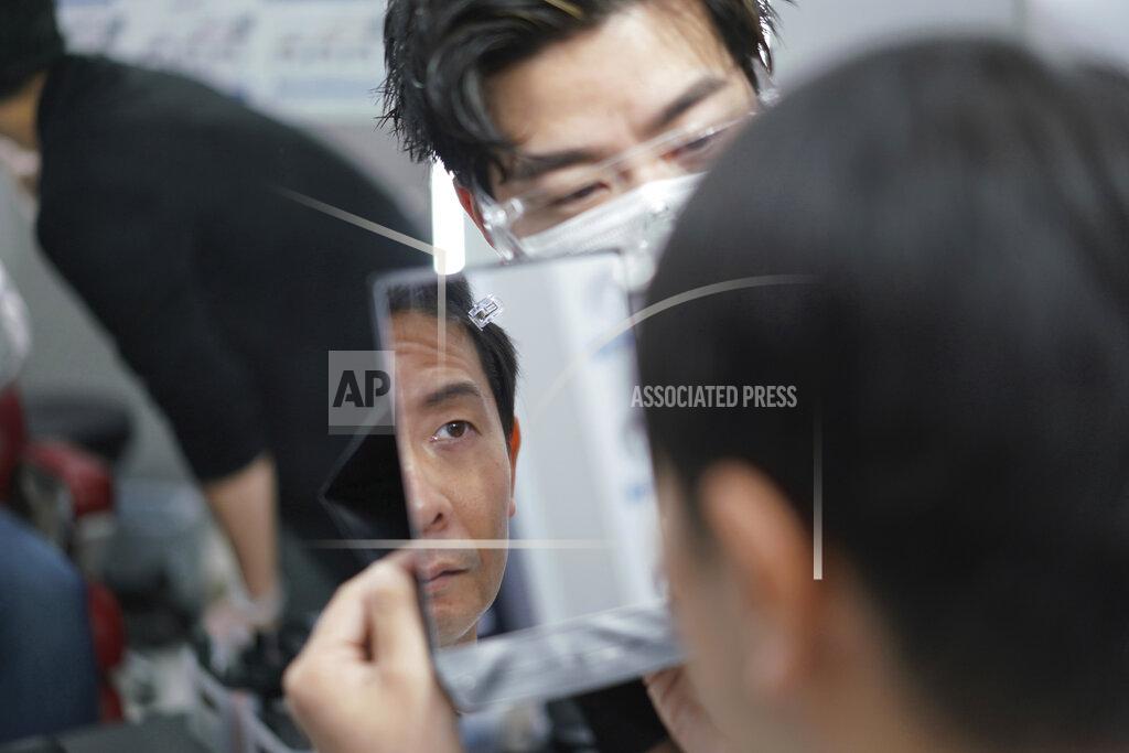 Eugene Hoshiko Yoshihiro Kamichi, a 44-year-old office worker, checks his face in a mirror as he receives makeup and gets his hair done by a makeup artist at Ikemen-Works, a makeup salon for men, in Tokyo Wednesday, Feb. 3, 2021. The coronavirus pandemic has been pushing businesses to the edge in Japan, but some in the men's beauty industry have seen an unexpected expansion in their customer base. Japanese businessmen in their 40s, 50s and 60s who had little interest in cosmetics before the pandemic are now buying makeup. (AP Photo/Eugene Hoshiko)