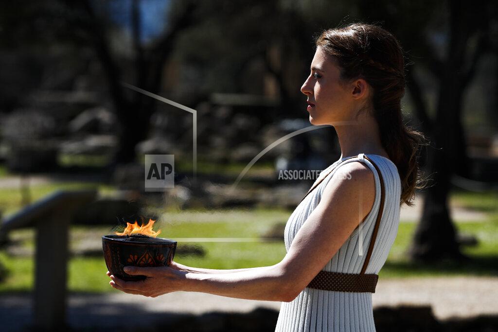 Thanassis Stavrakis An actress, playing the role of a priestess, holds the flame during the flame lighting ceremony at the closed Ancient Olympia site, birthplace of the ancient Olympics in southern Greece, Thursday, March 12, 2020. Greek Olympic officials are holding a pared-down flame-lighting ceremony for the Tokyo Games due to concerns over the spread of the coronavirus. Both Wednesday's dress rehearsal and Thursday's lighting ceremony are closed to the public, while organizers have slashed the number of officials from the International Olympic Committee and the Tokyo Organizing Committee, as well as journalists at the flame-lighting. (AP Photo/Thanassis Stavrakis)