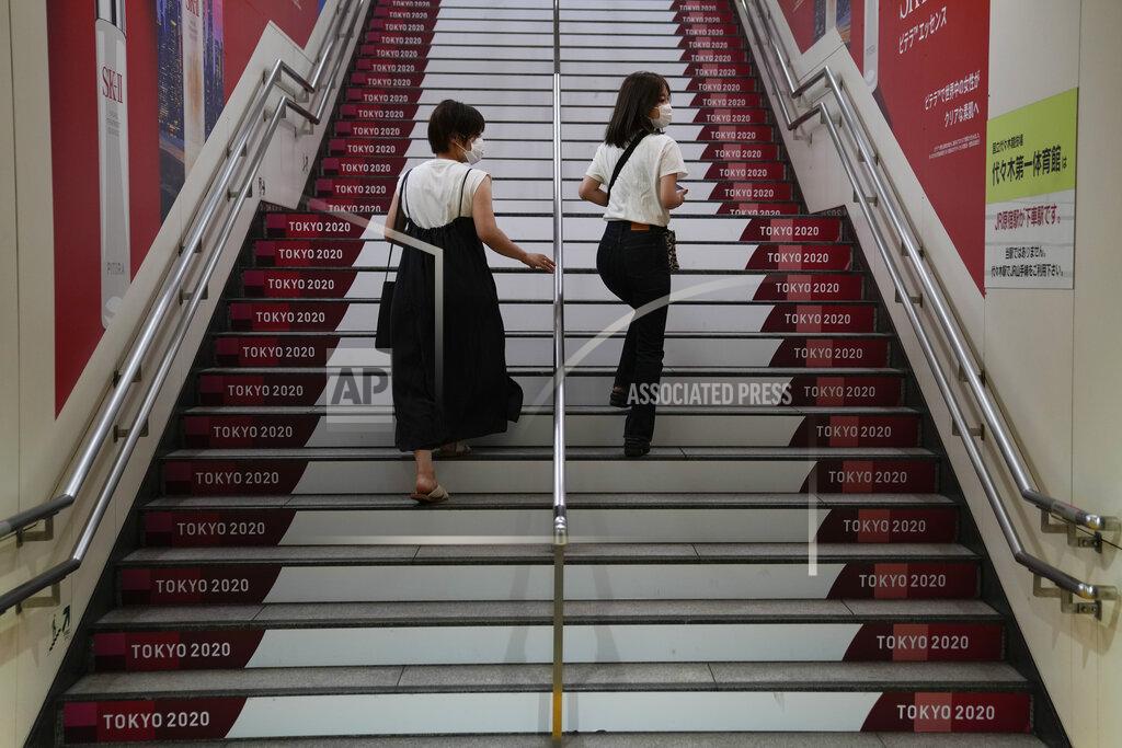 Jae C. Hong FILE - In this July 29, 2021, file photo, two women walk up the steps of a subway station adorned with Tokyo 2020 signs near the Olympic Stadium during the 2020 Summer Olympics in Tokyo, Japan. (AP Photo/Jae C. Hong, File)