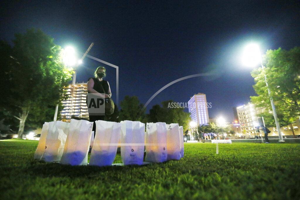 Briana Sanchez In this Thursday, July 30, 2020 photo, Mary Stockwell-White pauses at the 23 luminarias lit at Cleveland Square Park honoring the victims of the Aug. 3, 2019 El Paso shooting, in downtown El Paso. Stockwell-White is a registered nurse from Bellingham, Wash., who is passing through and wanted to pay her respects to the community for the anniversary. (Briana Sanchez/The El Paso Times via AP)