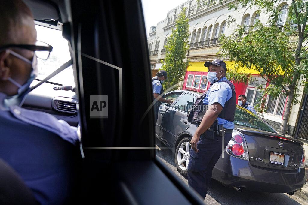 David Goldman Patrolman George Newell, left, checks on fellow police officers while patrolling through the Auburn Gresham neighborhood in Chicago, Tuesday, Aug. 25, 2020. In a chaotic year destined for the history books, Auburn Gresham has written its own grim chapter. This Black community on the city's South Side has endured a deadly virus, gun violence and economic misery, a constant state of turmoil that mirrors the tumult afflicting much of urban America. (AP Photo/David Goldman)