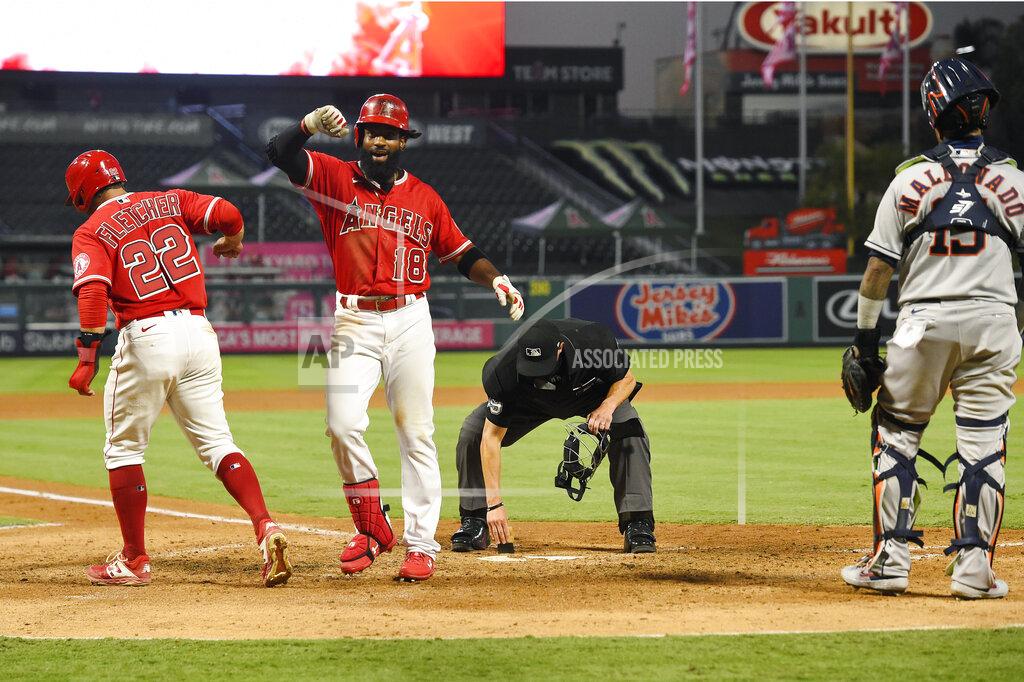 Mark J. Terrill Los Angeles Angels' Brian Goodwin, second from left, is congratulated by David Fletcher, left, as Houston Astros catcher Martin Maldonado, right, stands by and home plate umpire Cory Blaser wipes the plate after Goodwin hit a two-run home run during the fourth inning of a baseball game Friday, July 31, 2020, in Anaheim, Calif. (AP Photo/Mark J. Terrill)