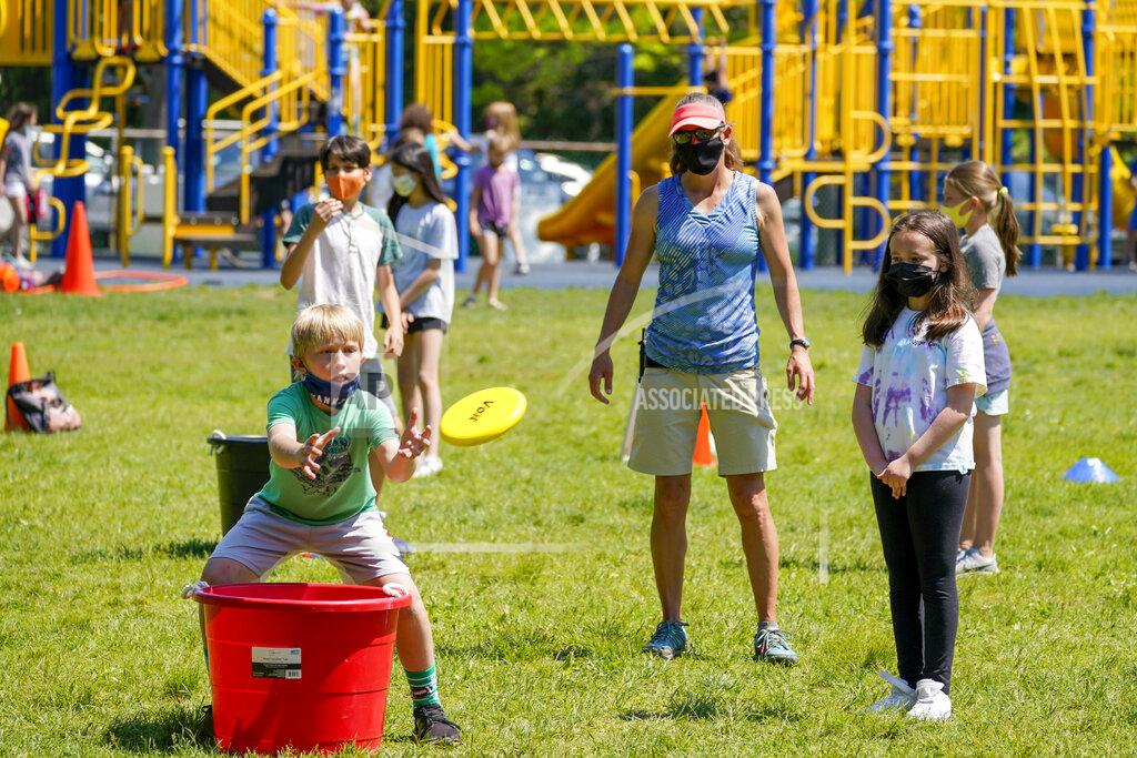 Mary Altaffer FILE - Gym teacher Becky Ward, center, watches as fifth graders throw frisbees at the Milton Elementary School, Tuesday, May 18, 2021, in Rye, N.Y. Gov. Andrew Cuomo said Monday that students no longer have to wear masks while outdoors on school grounds. But students and staff will still have to wear masks for the rest of the school year. (AP Photo/Mary Altaffer, File)