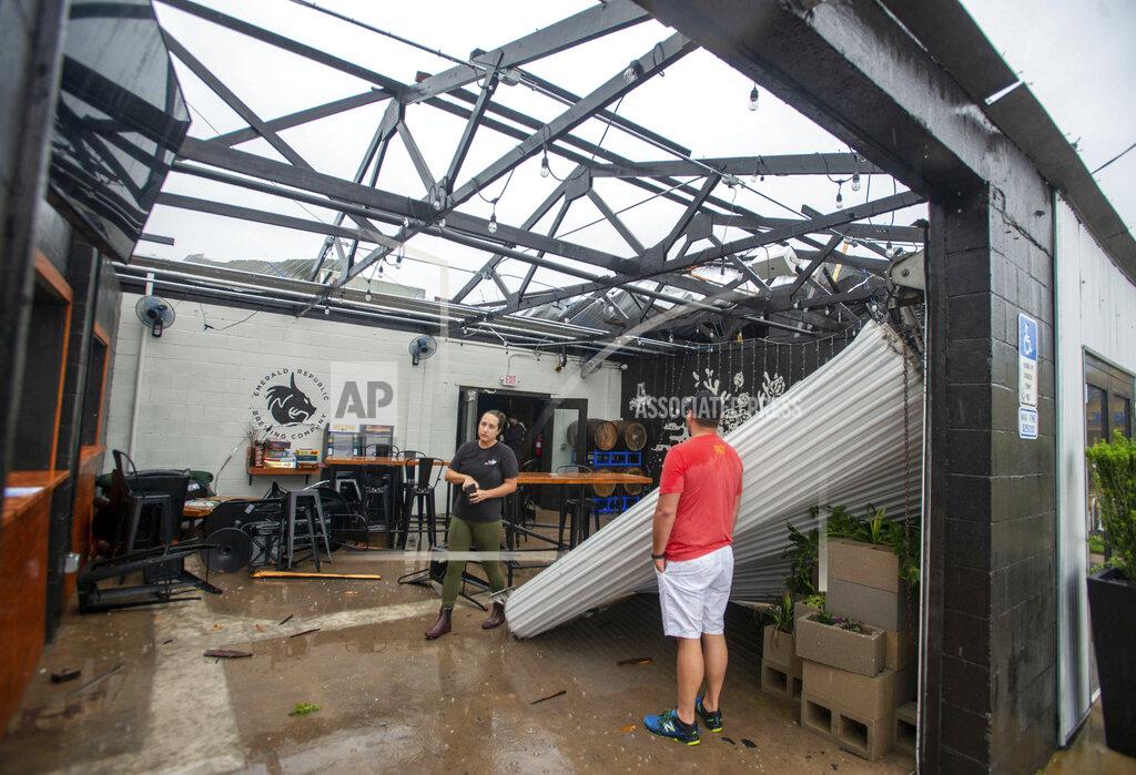 John Blackie Employees assess the damage after the storm that came through Pensacola, Fla., and blew the roof off of Emerald Republic Brewing on Saturday, April 10, 2021. (John Blackie/Pensacola News Journal via AP)