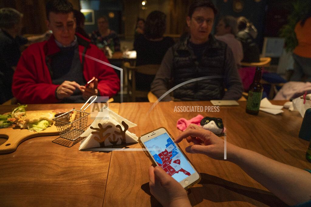 Ng Han Guan Attendees monitor electoral maps on their mobile phones during an election watch event held by Democrats Abroad at a restaurant in Beijing, China on Wednesday, Nov. 4, 2020. President Donald Trump and his Democratic challenger, Joe Biden, are in a tight battle for the White House. (AP Photo/Ng Han Guan)