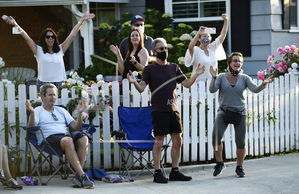 Chris Pizzello In this May 9, 2020 photo, SAG-AFTRA president Gabrielle Carteris, far right, and her husband Charles Isaacs, center, are among the cheering spectators at musician Adam Chester's weekly neighborhood performance in the Sherman Oaks section of Los Angeles. Normally, Chester is a surrogate Elton John, who sings and plays the rock superstar's parts at rehearsals. With that work on hold, Chester has been giving concerts to his neighbors from a safe social distance in front of his house. (AP Photo/Chris Pizzello)