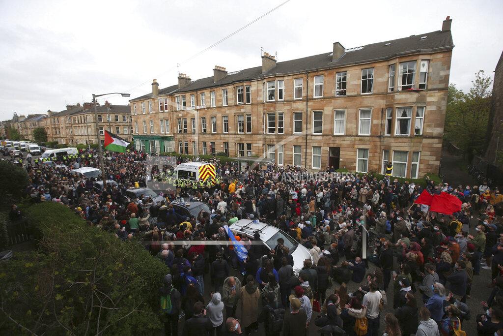 Andrew Milligan Police surround an immigration van in Kenmure Street which is surrounded by protesters, Thursday May 13, 2021, in Glasgow, Scotland. Protesters blockaded a street in Glasgow on Thursday in a seven-hour standoff which successfully forced the release of two men detained by U.K. immigration authorities. Hundreds of demonstrators filled the road in Scotland’s largest city to prevent a van leaving with the men inside, before police finally announced they would be freed. (Andrew Milligan/PA via AP)