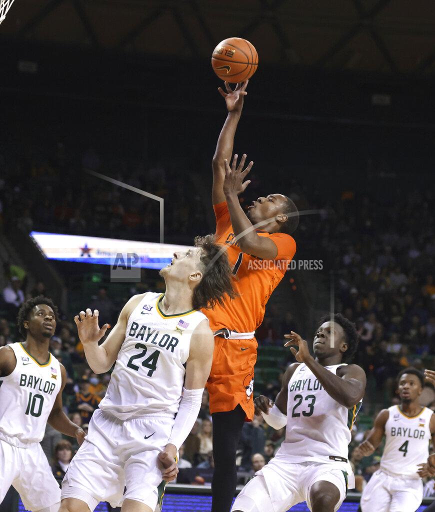 Rod Aydelotte Oklahoma State guard Bryce Thompson, center, pulls up while shooting over Baylor's Matthew Mayer, left, and Jonathan Tchamwa Tchatchoua, right, in the first half of an NCAA college basketball game, Saturday, Jan. 15, 2022, in Waco, Texas. (Rod Aydelotte/Waco Tribune Herald, via AP)
