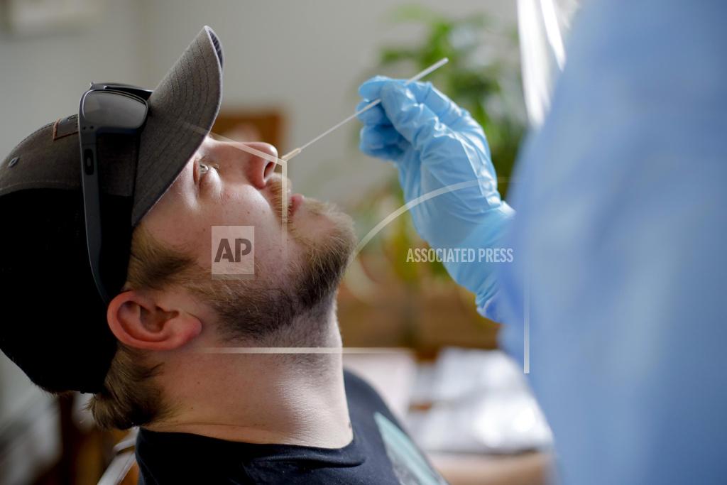 Stephanie Zollshan FILE - In this April 21, 2020, file photo, BFAIR shared living home staff member Matthew Donahue receives a COVID-19 swab test in Pittsfield, Mass. At a cost of $120-130 per test, and NHL Commissioner Gary Bettman’s estimate the league will need 25,000-35,000 in total to get through the playoffs, the price tag he concedes is “millions of dollars.” But regular testing is something players insisted on in the name of feeling safe to compete. (Stephanie Zollshan/The Berkshire Eagle via AP, File)