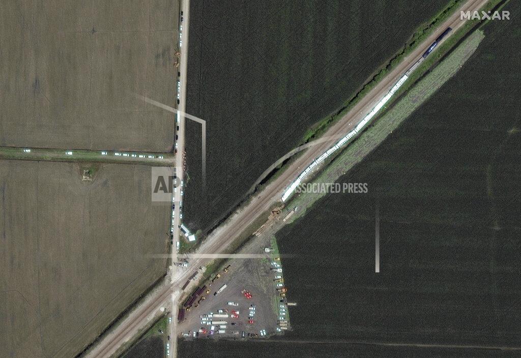 Uncredited This satellite image provided by Maxar shows an Amtrak train, at right, that derailed a day earlier along the rail line and dozens of cars, heavy lift equipment and rescue vehicles positioned nearby, Tuesday, June 28, 2022, near Mendon, Mo. (Satellite image ©2022 Maxar Technologies via AP)