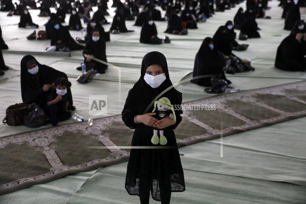 Vahid Salemi A girl wearing a protective face mask to help prevent spread of the coronavirus holds her doll as she attends a mourning ceremony to commemorate the 7th century death of Prophet Muhammad's grandson, Hussein, one of Shiite Islam's most beloved saints, who was killed in a battle in Karbala in present-day Iraq, at the Tehran University Musalla, Iran, Saturday, Aug. 29, 2020. The organizers arranged for the processions to take place with physical distancing, made face masks mandatory, checked mourners' body temperature and had them use hand sanitizers in an attempt to keep the gathering safe. Every year, millions of believers and followers of Shiite Islam flock to mosques for the ritual but this year the virus pandemic has scaled it down. (AP Photo/Vahid Salemi)
