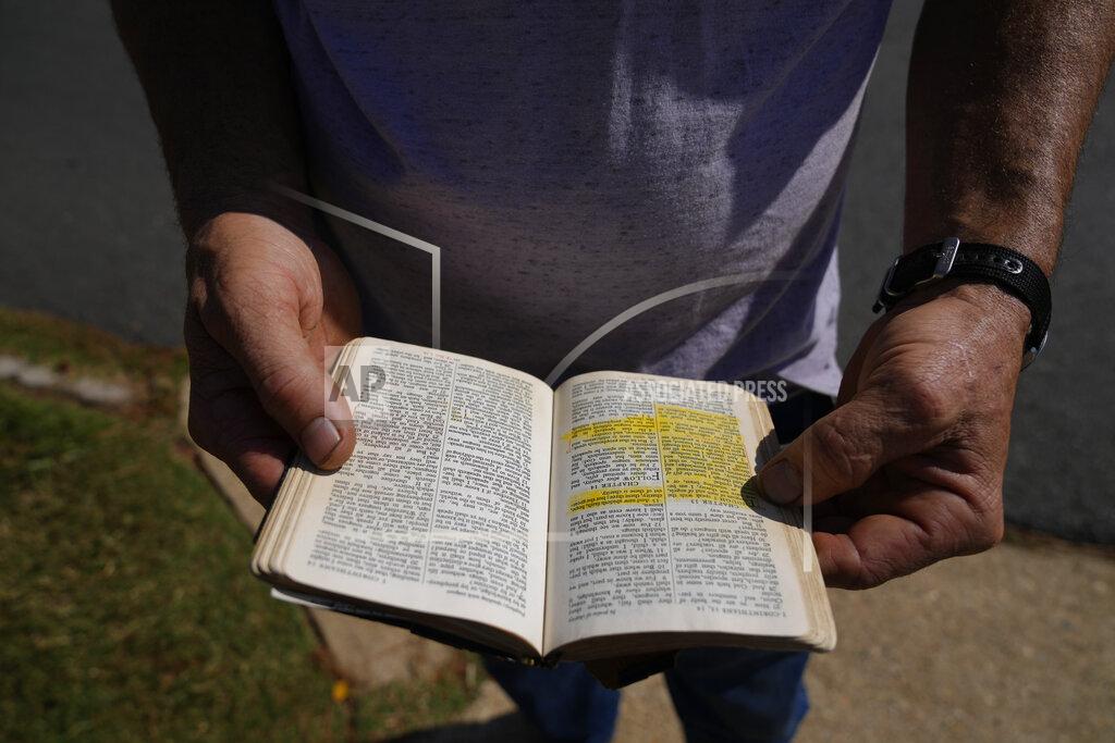 Rebecca Blackwell John Powers, 44, from Jacksonville, Texas, quietly reads a passage from a bible brought by a fellow anti-abortion protester, outside Hope Medical Group for Women, Saturday, Oct. 9, 2021, in Shreveport, La. Powers said he typically makes the nearly two-hour drive twice a month with the goal of getting any woman to change her mind. In the 13 years he's been protesting outside of clinics, he says he's successfully convinced two women not to go through with their abortions, which he calls "turnarounds." (AP Photo/Rebecca Blackwell)