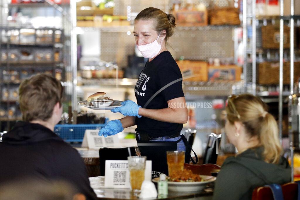 Jamie Ferrell serves customers at Puckett's Grocery & Restaurant Monday, April 27, 2020, in Franklin, Tenn. Monday is the first day Tennessee restaurants can reopen with reduced seating and social distancing during the coronavirus pandemic.(AP Photo/Mark Humphrey)