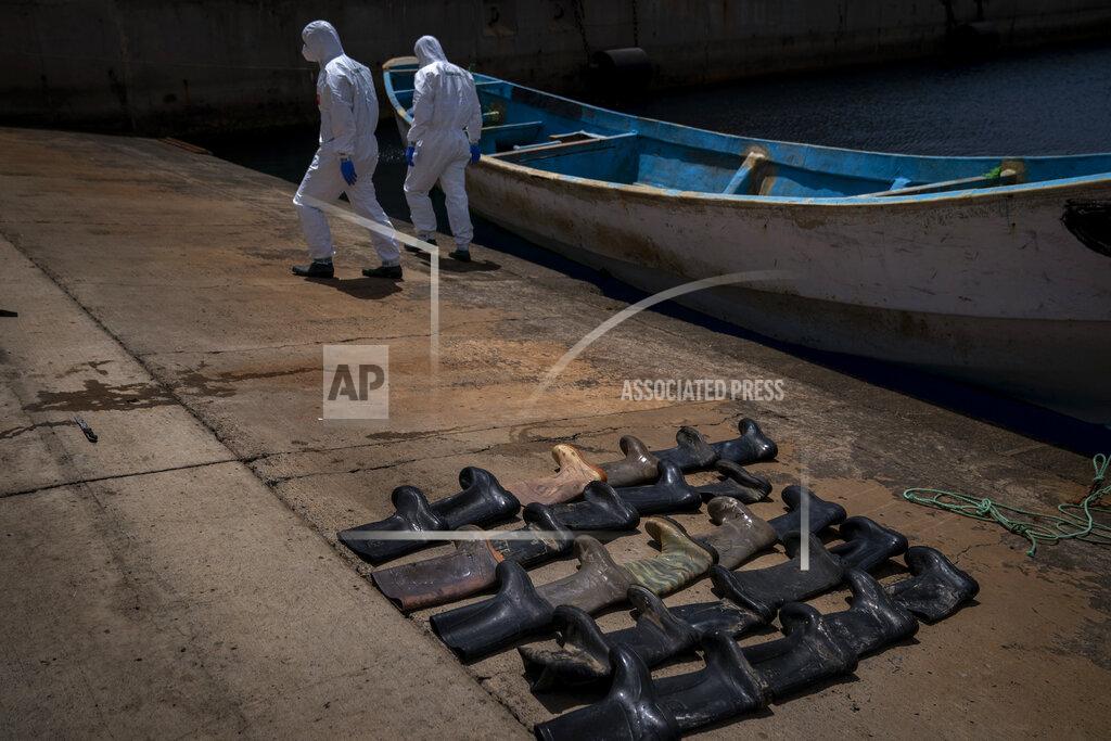 Emilio Morenatti Waterproof boots are placed on the ground by police officers as they inspect a boat where 15 Malians were found dead adrift in the Atlantic on Thursday, Aug. 20, 2020 in Gran Canaria island, Spain. (AP Photo/Emilio Morenatti)
