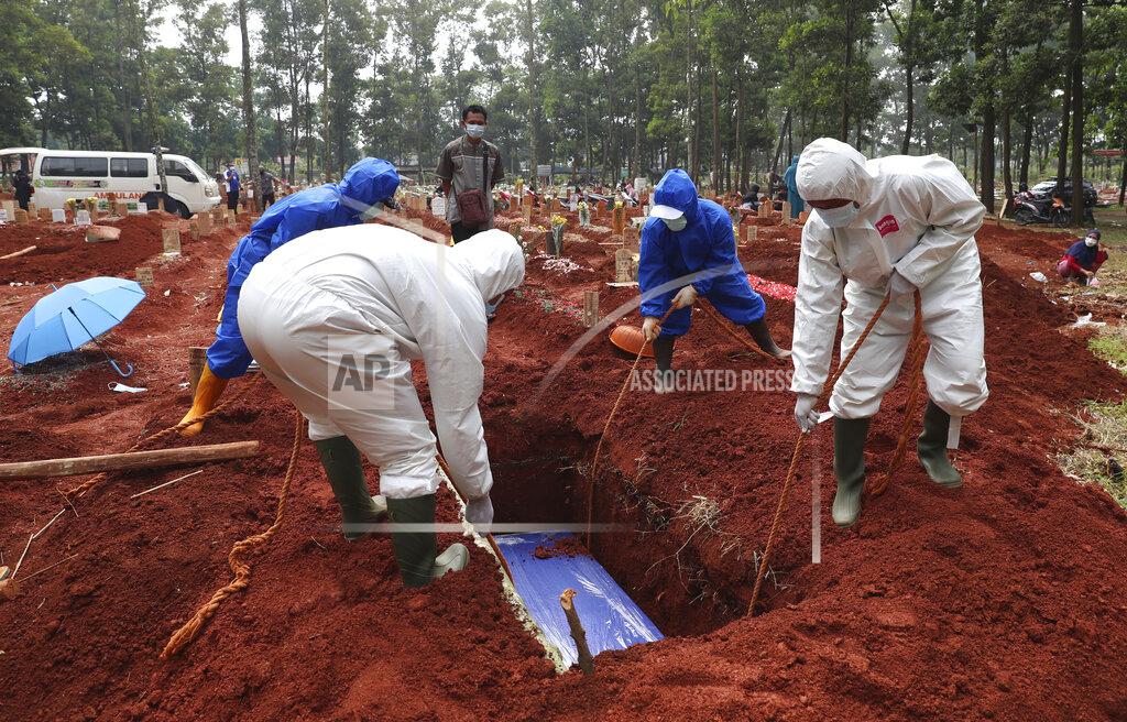 Achmad Ibrahim In this July 14, 2021, photo, workers in protective gear lower a coffin of a COVID-19 victim to a grave for burial at the Cipenjo Cemetery in Bogor, West Java, Indonesia. Images of bodies burning in open-air pyres during the peak of the pandemic in India horrified the world in May, but in the last two weeks Indonesia and two other Southeast Asian nations have surpassed India’s peak per capita death rate as a new coronavirus wave tightens its grip on the region. (AP Photo/Achmad Ibrahim)