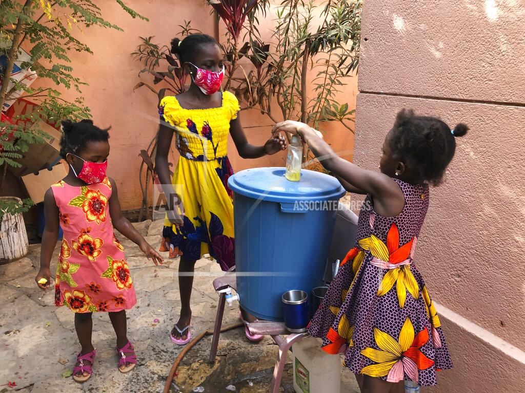 In this May 21, 2020, photo, the Larson sisters wash their hands inside the gate at their home in Dakar, Senegal. The girls were adopted from Sierra Leone after their father and other relatives died of Ebola. (AP Photo/Krista Larson)