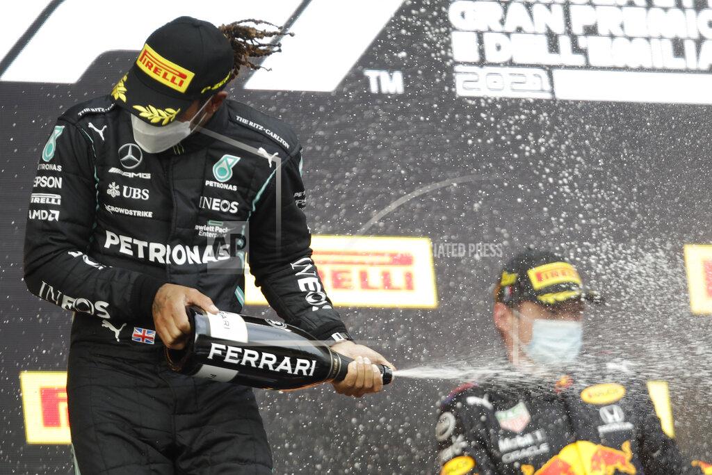 Luca Bruno Second placed Mercedes driver Lewis Hamilton of Britain sprays sparkling wine on winner Red Bull driver Max Verstappen of the Netherlands, after the Emilia Romagna Formula One Grand Prix, at the Imola racetrack, Italy, Sunday, April 18, 2021. (AP Photo/Luca Bruno)