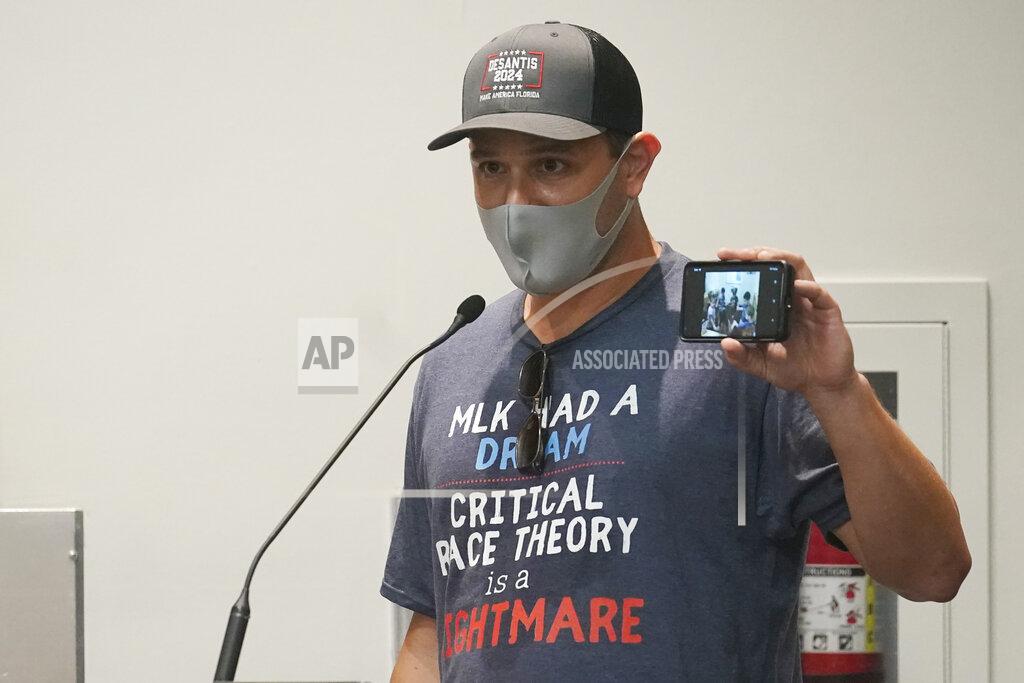 Marta Lavandier Elon Gerberg holds up a picture of his two young children singing and dancing at a private daycare, during the Broward School Board's emergency meeting, Wednesday, July 28, 2021, in Fort Lauderdale, Fla. The board listened to parents' concerns and will make a decision regarding the use of masks for K-12 students in the upcoming school year. (AP Photo/Marta Lavandier)