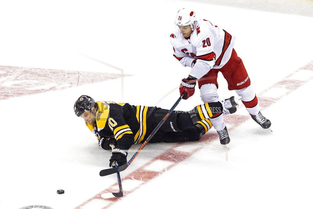 Chris Young Boston Bruins' Anders Bjork (10) falls in front of Carolina Hurricanes' Sebastian Aho (20) during the third period of an NHL Eastern Conference Stanley Cup hockey playoff game in Toronto, Thursday, Aug. 13, 2020. (Chris Young/The Canadian Press via AP)