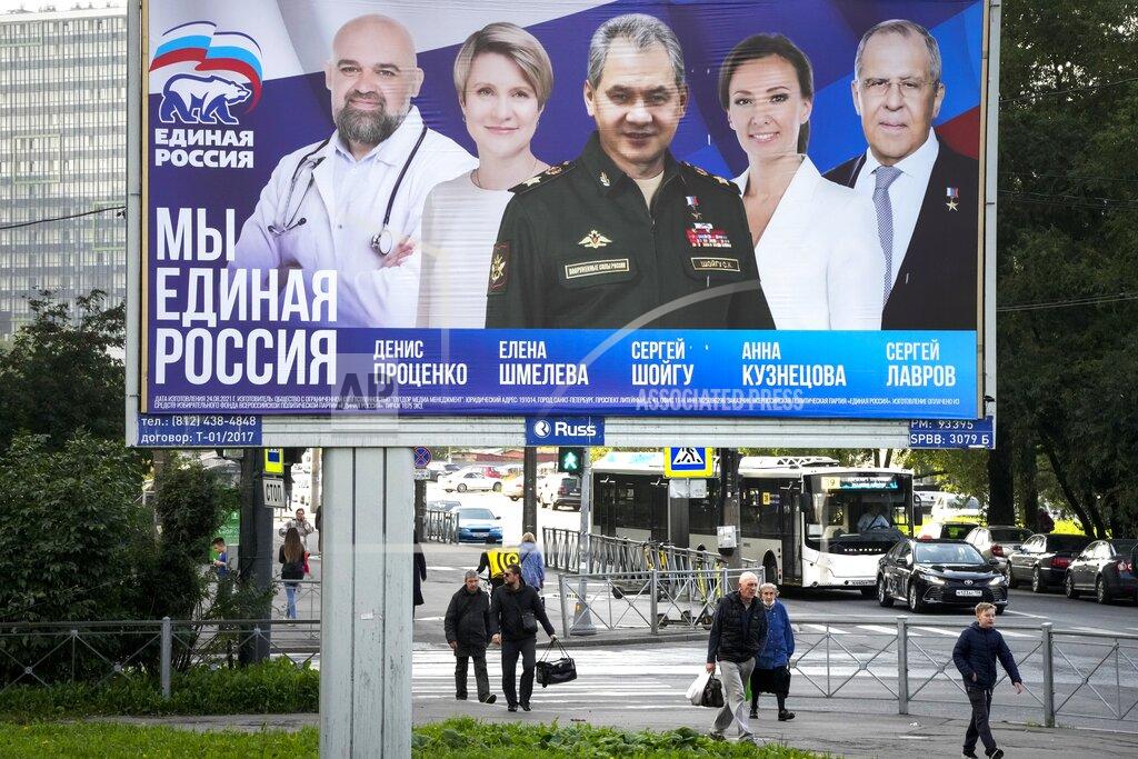 Dmitri Lovetsky People walk past an election poster in St. Petersburg, Russia, on Saturday, Sept. 11, 2021, ahead of the upcoming election for the State Duma, the lower house of the Russian parliament. The poster, from left, shows Denis Protsenko, head of the educational foundation "Talent and Success"; Yelena Shmeleva; Russian Defense Minister Sergei Shoigu; children's rights ombudsman Anna Kuznetsova; and Russian Foreign Minister Sergey Lavrov, candidates of the pro-Kremlin United Russia Party during the campaign. (AP Photo/Dmitri Lovetsky)
