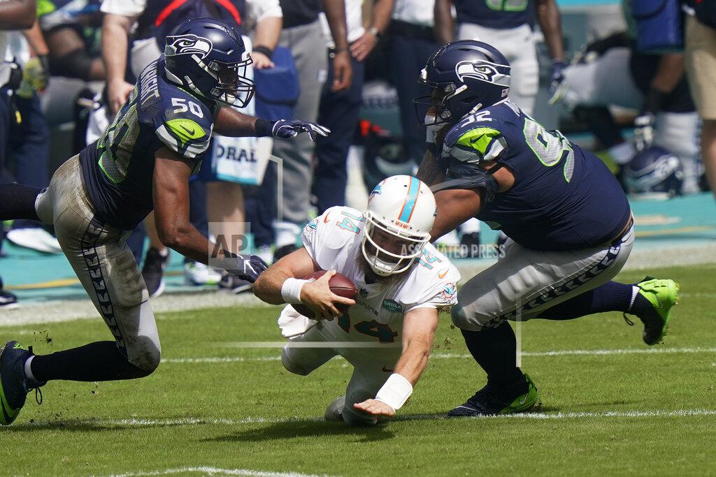 Lynne Sladky Miami Dolphins quarterback Ryan Fitzpatrick (14) falls as Seattle Seahawks outside linebacker K.J. Wright (50) and defensive tackle Bryan Mone (92) attempt to tackle, during the second half of an NFL football game, Sunday, Oct. 4, 2020, in Miami Gardens, Fla. (AP Photo/Lynne Sladky)