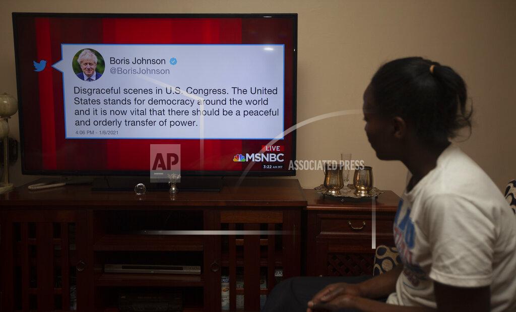 Sayyid Abdyl Azim A Kenyan watches a news report on Kenyan TV, Thursday, Jan. 7, 2021, showing Britain's Prime Minister Boris Johnson Twitter comment among World leaders reaction to the U.S. Capitol demonstrations on Wednesday, Jan. 6, 2021, in Washington, USA. (AP Photo/Sayyid Abdul Azim)