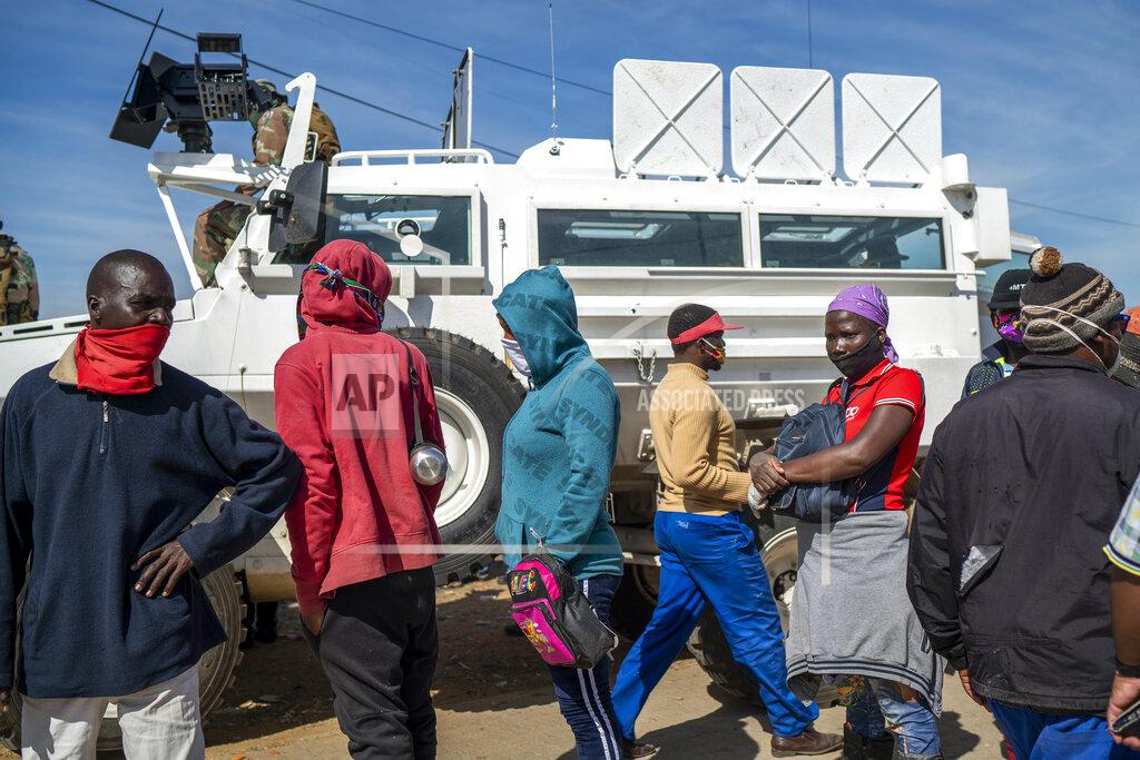 People line up to receive food handouts in the Olievenhoutbos township of Midrand, South Africa, Saturday May 2, 2020. though South Africa begun a phased easing of its strict lockdown measures on May 1, its confirmed cases of coronavirus continue to increase. (AP Photo/Jerome Delay)