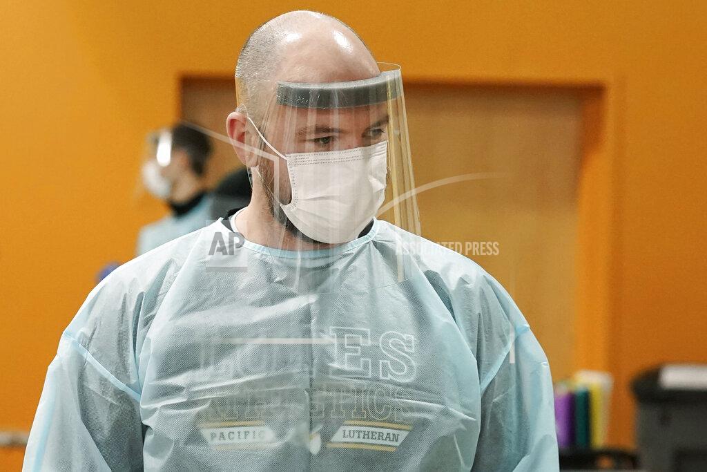 Ted S. Warren Brant McAdams, head football coach at Pacific Lutheran, wears personal protective equipment as he administers COVID-19 tests for student athletes Wednesday, Feb. 3, 2021, on campus in Tacoma, Wash. There was never a chapter in any of the books on becoming a small NCAA college football coach that addressed administering COVID-19 tests in the midst of a pandemic, but now it's something he's doing to give his players the chance at a season. (AP Photo/Ted S. Warren)