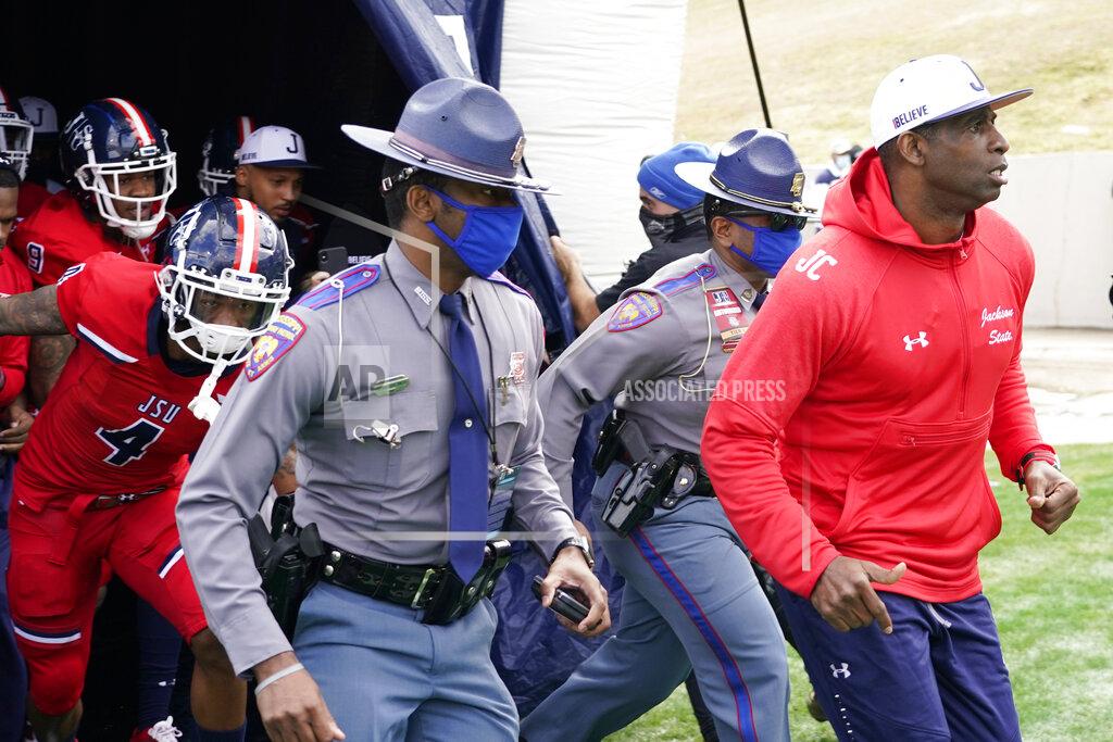 Rogelio V. Solis Jackson State football coach Deion Sanders, right, leads an accompanying security detail and his team onto the field prior to the first half of an NCAA college football game against Edward Waters in Jackson, Miss., Sunday, Feb. 21, 2021. The game marks Sanders's collegiate head coaching debut. (AP Photo/Rogelio V. Solis)