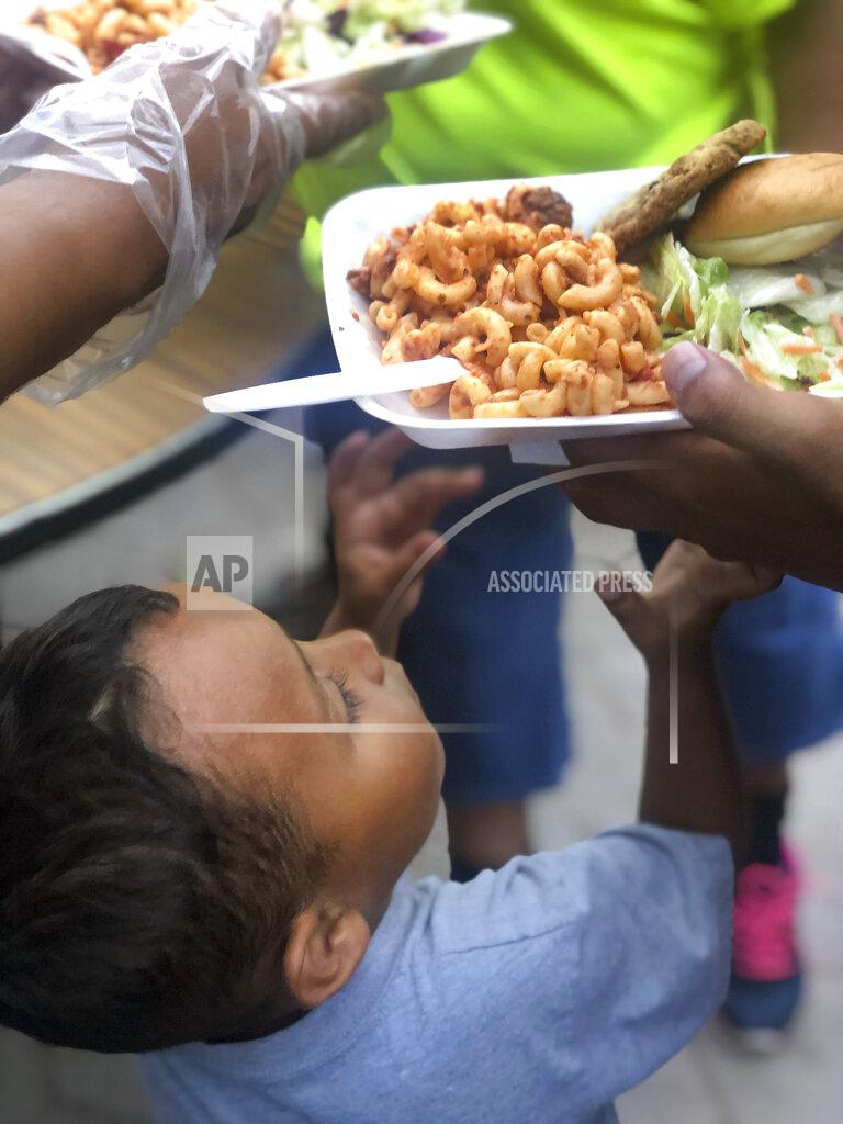 Daniela Dominguez In this October 2019 photo provided by Daniela Dominguez, a child reaches for a meal cooked by a team from the Bay Area Border Relief at a tent encampment in Matamoros, Mexico. Dominguez, assistant professor in counseling psychology at University of San Francisco, said mutual aid networks are part of the Latino culture where people may feel safer getting help from their own community rather than government entities or formal charities. (Daniela Dominguez via AP)