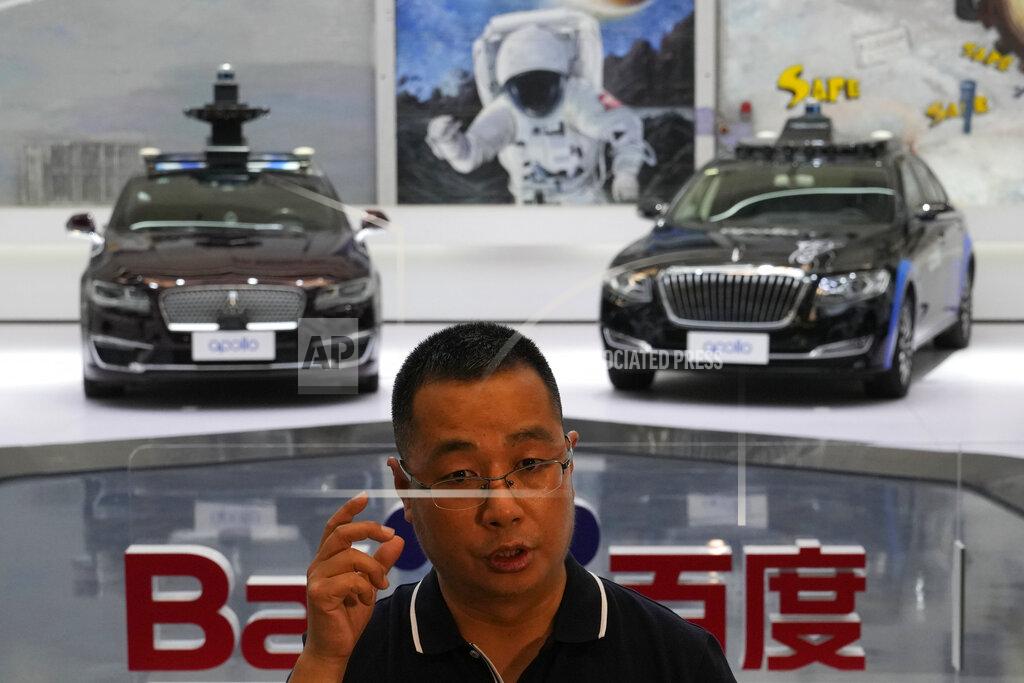 Ng Han Guan Wei Dong, vice president of Baidu's Intelligent Driving Group, speaks near a display showing the various prototypes of the self-driving taxi developed by tech giant Baidu Inc. on June 14, 2022, in Beijing. Baidu Inc. is China's highest-profile competitor in a multibillion-dollar race with Alphabet Inc.'s Waymo and General Motors Co.'s Cruise to create self-driving cars. (AP Photo/Ng Han Guan)
