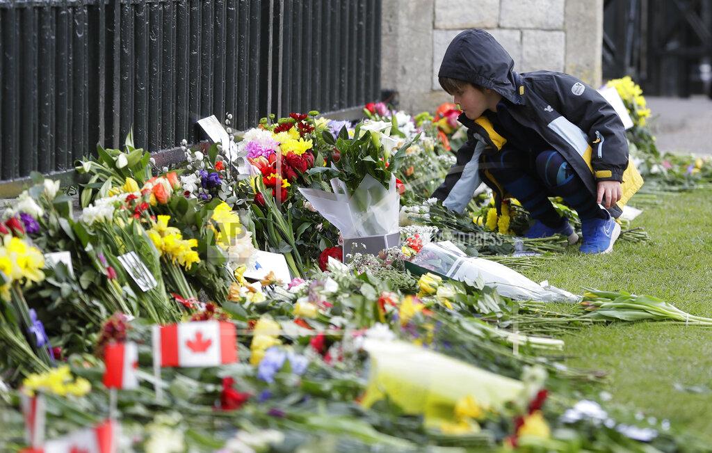 Kirsty Wigglesworth A child leaves flowers outside Windsor Castle in Windsor, England Sunday, April 11, 2021. Britain's Prince Philip, the irascible and tough-minded husband of Queen Elizabeth II who spent more than seven decades supporting his wife in a role that mostly defined his life, died on Friday. (AP Photo/Kirsty Wigglesworth)