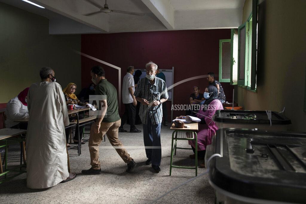 Nariman El-Mofty Election workers help people prepare to cast their ballots on the first day of the parliamentary election inside a polling station in Giza, Egypt, Saturday, Oct. 24, 2020. Egyptians began voting Saturday in the first stage of a parliamentary election, a vote that is highly likely to produce a toothless House of Representatives packed with supporters of President Abdel-Fattah el-Sissi. (AP Photo/Nariman El-Mofty)
