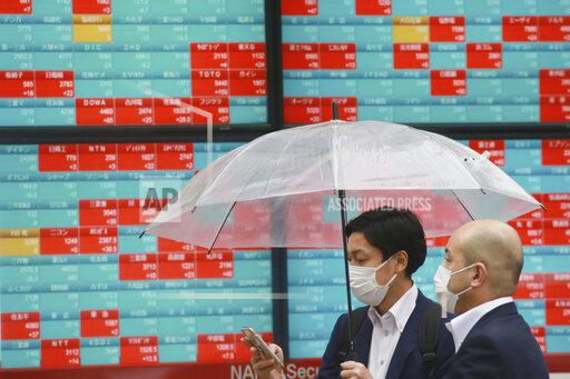 People walk by an electronic stock board of a securities firm in Tokyo, Wednesday, Oct. 13, 2021. Shares were mixed in Asia on Wednesday after an up-and-down day on Wall Street ended with most benchmarks lower as traders waited for updates on inflation and corporate
earnings. (AP Photo/Koji Sasahara)
