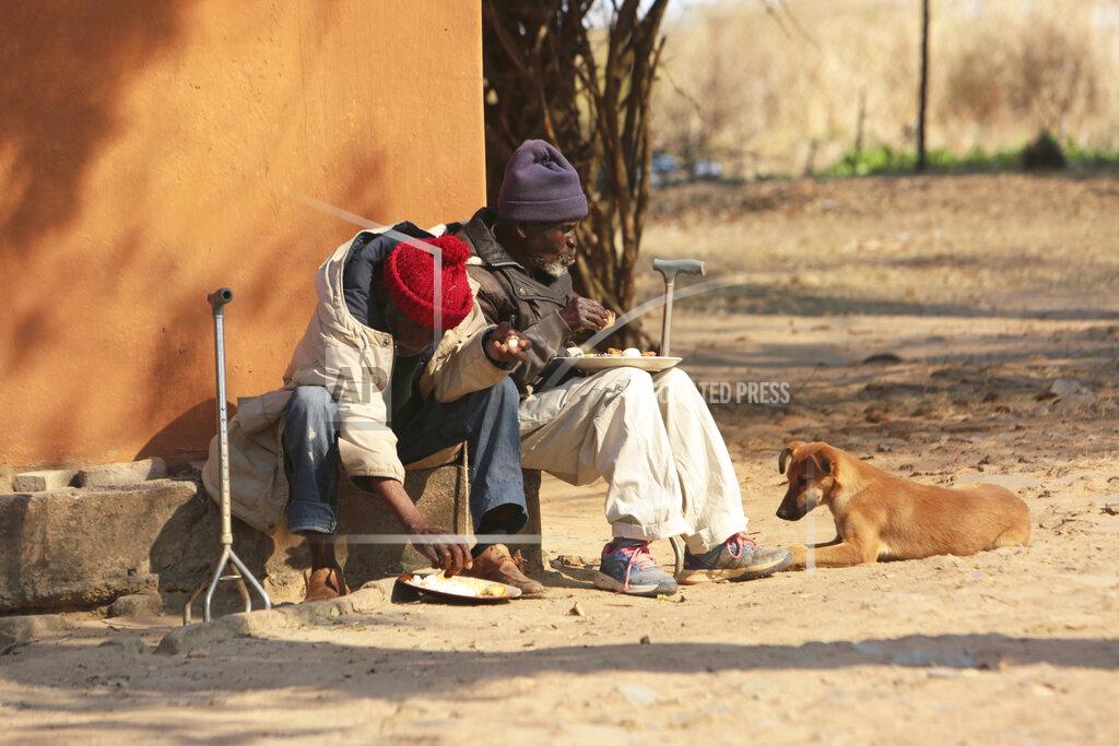 Tsvangirayi Mukwazhi Elderly men have lunch at Melfort Old People's home on the outskirts of Harare, Zimbabwe, Sunday, July 25, 2021. The economic ravages of COVID-19 are forcing some families in Zimbabwe to abandon the age old tradition of taking care of the elderly. Zimbabwe's care homes have experienced a 60% increase in admissions since the outbreak of the pandemic in March last year. (AP Photo/Tsvangirayi Mukwazhi)