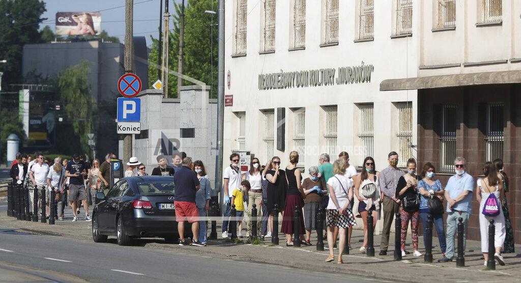 Czarek Sokolowski People wearing protective face masks observe mandatory social distancing against the spread of the coronavirus as they wait in line to cast their votes in Poland's presidential election. The election will test the popularity of incumbent President Andrzej Duda who is seeking a second term and of the conservative ruling party that backs him, in Warsaw, Poland, Sunday, June 28, 2020. (AP Photo/Czarek Sokolowski)